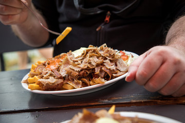 Mann isst Döner Kebab Teller mit Pommes, Salat, Scharf und Knoblauch Sauce