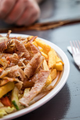 Mann bei gemeinsamer Mittagspause mit Döner Kebab Teller mit Pommes, Salat, Scharf und Knoblauch Sauce