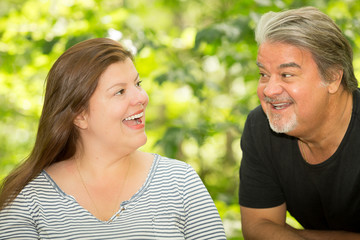 Obraz premium Outdoor portrait of latin couple sharing a day in the park. They are both happily looking at each other. They are both Caucasian with smooth hair and brown eyes.