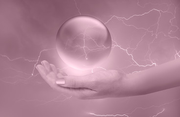 A woman hand holding a glowing crystal ball with ligthning