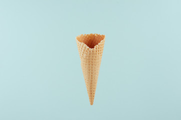 Empty  waffle ice cream cone on soft light pastel green background, mock up for advertising, design, menu, summer food.