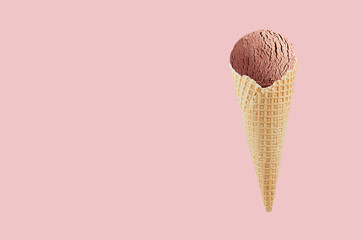 Chocolate ice cream in crisp waffle cone on pastel pink background, mock up for design, summer food.