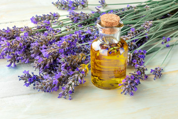Lavender essential oil with lavender flowers on a rustic wooden background with copyspace. A glass bottle with a cork with buds infusing