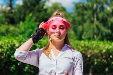 Portrait of an emotional girl in a pink cap visor and protective gloves for rollerblades and...