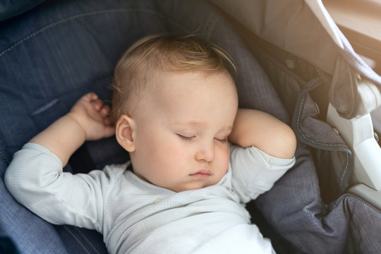 Cute adorable caucasian blond toddler bou sleeping in stroller at daytime. Children healthcare and happy childhood concept
