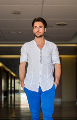 Waist Up Portrait of Attractive Young Man Wearing Shirt Standing Looking Thoughtful in Hallway of School or Shopping Mall