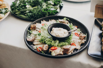 Modern Caesar salad. Smoked meat,sauce,cheese, parmesan, tomato, salad on plate at wedding or christmas feast. Luxury catering concept. Delicious italian food table at wedding reception.