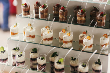 Delicious candy bar at wedding reception. White and chocolate desserts with fruits and cream,...