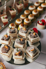 White and chocolate desserts with fruits and crem,  cupcakes on stand, modern sweet table at wedding or baby shower. Luxury catering concept. Delicious candy bar at wedding reception.