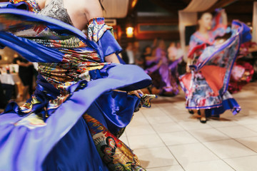 Beautiful gypsy girls dancing in traditional colorful clothing. Roma gypsy festival. Woman performing romany dance and singing folk songs in national dresses at wedding reception