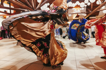 Beautiful gypsy girls dancing in traditional gold floral dress at wedding reception in restaurant....