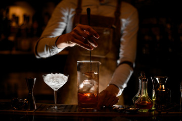Bartender stirring a cocktail in the measuring glass cup