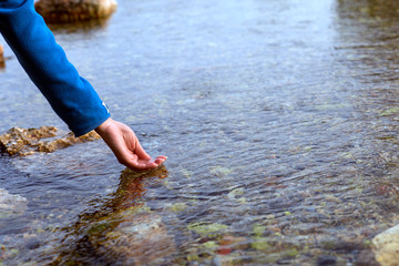 The human hand cupped to catch the fresh water from clear lake.