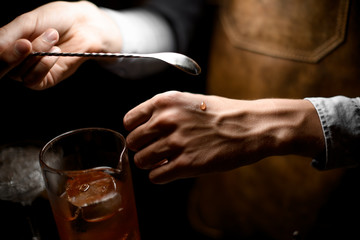 Bartender holding a spoon and put a drop on the hand
