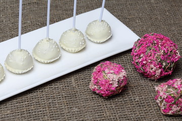 Fototapeta na wymiar Cake pops in white chocolate glaze. Stand vertically on a stand. Decorated with white decorative sprinkles. Near rattan balls.