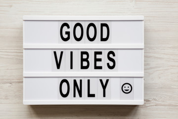 'Good vibes only' words on a modern board on a white wooden background, top view. From above, overhead, flat lay. Close-up.