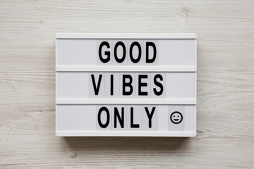 'Good vibes only' words on a modern board on a white wooden surface, top view. From above, overhead, flat lay.