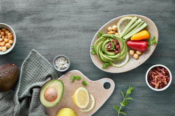 Keto diet, close-up on avocado rose with bacon cubes and smoked cheese seasoned with lemon, mint leaf and sea salt