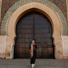Tourist by authentic gate in Meknes, Morocco