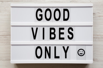 Overhead view, 'Good vibes only' words on a lightbox on a white wooden background, top view. From above, overhead, flat lay.