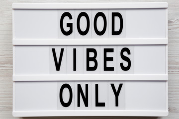 'Good vibes only' words on a modern board on a white wooden surface, top view. From above, overhead, flat lay. Close-up.