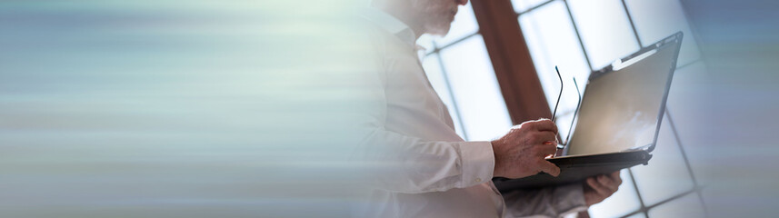 Senior businessman working on laptop. panoramic banner