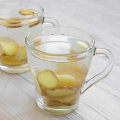 Homemade ginger tea with lemon on a white wooden background, side view. Close-up.