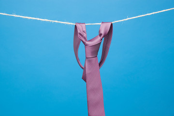Corbata con su nudo clásico hecho, en una cuerda sujeto con pinzas clásicas de madera de tender...