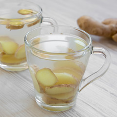 Homemade ginger tea with lemon on a white wooden background, side view. Close-up.