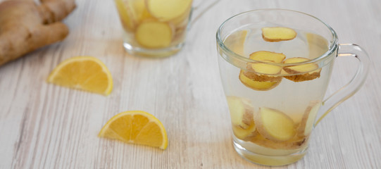 Homemade ginger tea with lemon on a white wooden background, low angle view. Close-up.