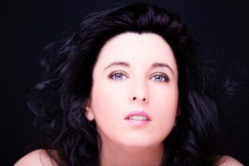 Fototapeta premium Young attractive woman with long black hair on dark background