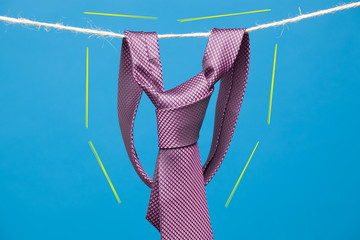 Corbata con su nudo hecho y colgada de una cuerda y sujeta por pinzas de madera de extender la ropa
