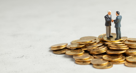 Businessmen shake hands as a symbol of a successful profitable transaction. Businessmen on a stack of gold coins as a symbol of success or successful investments