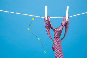 Nudo de corbata clásica, colgada de una cuerda y sujeta por pinzas de madera de colgar la ropa....