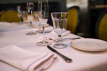 Natural light or daylight shot of modern restaurant table set for a lunch. Shallow focus on wine glass. Empty glasses set in restaurant.