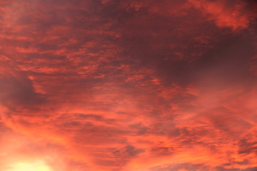 purple red alarming sunset sky with blood orange clouds and bright sunshine like fire