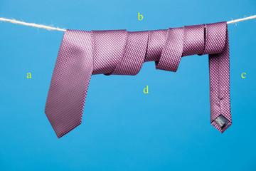 Corbata con su nudo clásico, colgada de una cuerda y sujeta por pinzas de madera de tender la ropa