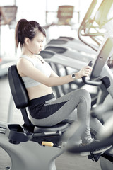asian woman working out at gym with cycle machine