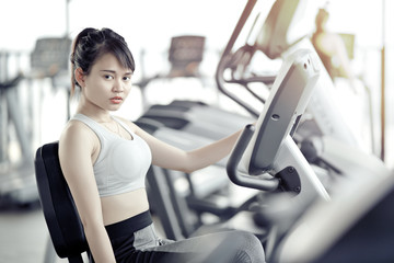 Fototapeta premium asian woman working out at gym with cycle machine