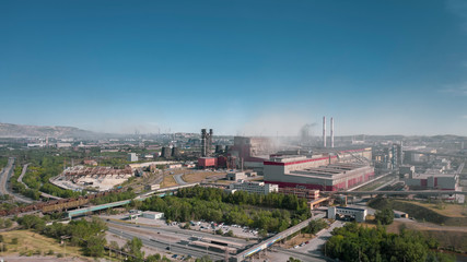 Obraz premium Concept of environmental pollution, drone view of smokestack pipe steel plant, aerial industrial panoramic landscape with blue sky and autumn vegetation, air emissions from manufacturing sector,Russia