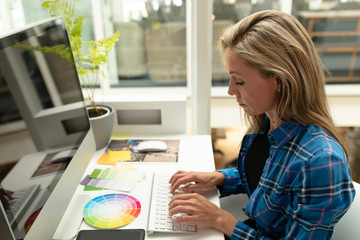 Fototapeta na wymiar Female graphic designer working on computer at desk