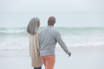 Couple holding hands while walking by the beach