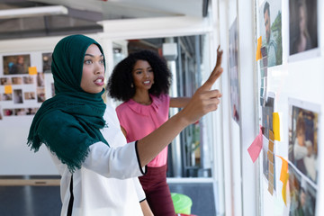 Female graphic designers discussing over photographs in office