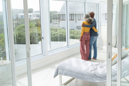 Couple Standing Close Together While Looking Out The Window