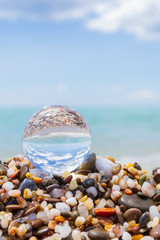 Glass round ball on the beach reflects the sea in summer