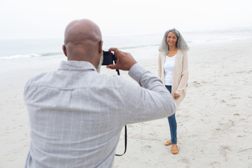 Man taking a picture of woman at the beach