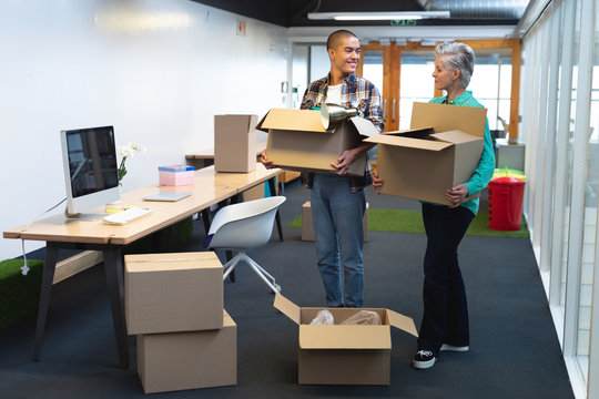 Male and female executives carrying cardboard boxes in office