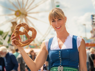 Junge, schöne Frau in Tracht mit Breze auf der Dult