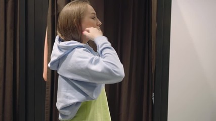 Pretty young beautiful woman trying on blue sweatshirt, shopping, casual clothes