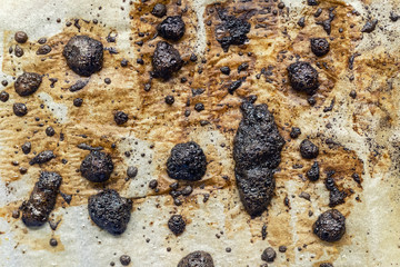 Burned fat stains on cooking parchmanet paper after oven food grillingn. Unhealthy cancer-causing...